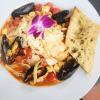 A plate of food that includes mussels, pasta and tomatoes.