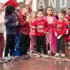 Preschool-aged children wearing red and green sing songs and ring jingle bells.