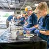 Children pour ingredients onto a gray powder on paper plates in Penn College's concrete lab.