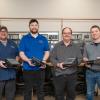 Four Penn College employees hold frames for human-machine interfaces.