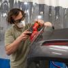 A Penn College student applies a Milwaukee random orbital sander to a vehicle bumper.