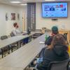People sitting around a long table in Penn College's Center for Career Design focus on a large video screen that shows a virtual meeting in progress.