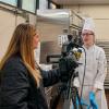 A woman with a television camera and microphone talks with a student in a chef uniform.