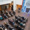 Overview of the lobby in Penn College's Davie Jane Gilmour Center, where the college president stands at a podium in front of a wall listing the names of donors, and people seated in chairs face him.