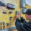 A student runs a control power wire to a thermostat in a Pennsylvania College of Technology building automation lab.