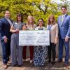 A group of people in business attire holds an oversize check.