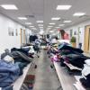 Two long rows of tables in the Penn College Center for Career Design are covered by neat stacks of clothing. A student looks through one of the stacks.