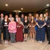 A large group of students in dressy clothes holding glass trophies.