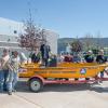 People stand in and around a bright yellow emergency rescue boat that is sitting on a trailer.