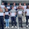 Students hold certificates while standing on the stairs outside of Penn College's College Avenue Labs building.