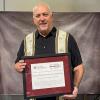 A man holds a framed certificate.