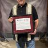 A man holds a framed certificate.