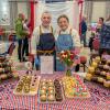 Two students in chefs uniforms and aprons stand behind a cupcake display.