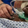 Closeup of a hand holding a stethoscope on the ches of a medical manikin.