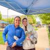 Two students stand under a tent on the campus mall. One is holding a snow cone and food wrapped in foil.