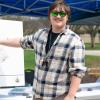 At an outdoor event, a student in sunglasses points to a map of Pennsylvania that has several pins in it.