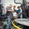 In Penn College’s Lycoming Engines Metal Trades Center, a faculty member demonstrates the handheld control for a robotic welder to participants in the Non-Destructive Technology Camp.