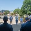 People in business clothing stand in a circle outside of Penn College's Davie Jane Gilmour Center, with the Bush Campus Center visible in the background.