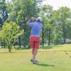 A golfer watches a shot after taking a swing on a golf course.