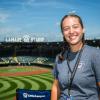 A woman smiles. Visible in the background is Lamade Stadium at Little League International.