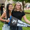 Two studnets stand outdoors holding a Penn College Wildcats pennant.