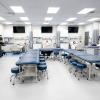 A view of the Penn College physician assistant program's Clinical Assessment Lab shows three hospital beds with manikins, large-screen monitors and other healthcare equipment, as well as several exam tables with equipment and cabinetry.