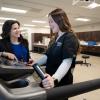 A Penn College physical therapist assistant program faculty member talks with a physical therapist assistant student who is standing on a treadmill. The student is wearing a shirt with the Penn College logo and the words "physical therapist assistant."