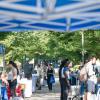 Students gather around tables and under blue canopies on a Penn College walkway.