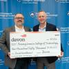 Two men in business attire hold an oversized check. They are standing in front of a step-and-repeat backdrop that has Pennsylvania College of Technology logos.