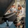 A Penn College student monitors the plastic flowing from an extrusion machine.