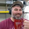 Robert Layng wears headphones and holds up a coffee cup.