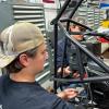 Two students prepare to mount an engine in a single-seat all-terain vehicle.
