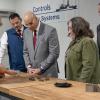 Five people look at machined pieces on a workbench in Penn College's Larry A. Ward Machining Technologies Center.