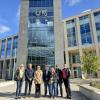 Six adults pose in front of a large building that displays the initials "SETU" and the logo for South East Technological University.