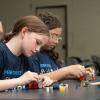 Middle school-aged girls assemble small Lego robots in a Penn College classroom.