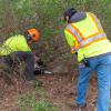 Chad L. Karstetter, horticulturist/motor pool lead person (and a 1999 forest technology alumnus), cuts with a chainsaw while Gregory A. Weaver, an HVAC-refrigeration mechanic, pulls brush.