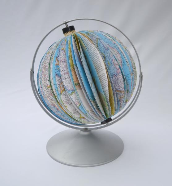 Janet Reynolds, Fragile Planet, 2022, discarded atlas, metal globe frame, 18” h x 13” w x 12” d